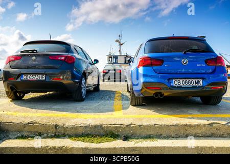 sozopol, burgas, bulgaria - 5 settembre 2019: due auto di lusso parcheggiate nel porto. alfa romeo giulietta nera e bmw 120d xdrive blu vista dal retro. it Foto Stock