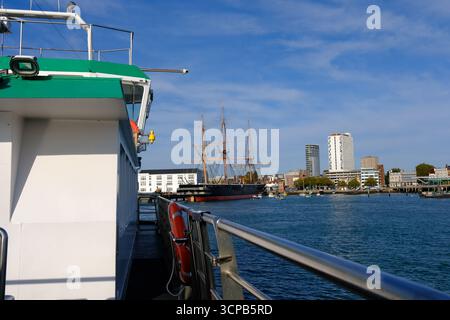 24 SETTEMBRE 2025 - Portsmouth, Regno Unito - lo storico veliero HMS Warrior al molo nel porto di Portsmouth e visto dal Gosport Ferry che attraversa la h Foto Stock