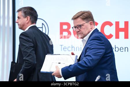 Gerlingen, Germania. 25 settembre 2025. Stefan Grosch (r), membro del Consiglio di amministrazione e direttore del lavoro della Robert Bosch GmbH, lascia la sala conferenze dopo una conferenza stampa sui tagli al lavoro. Sulla sinistra c'è Thomas Pauer, presidente della divisione Power Solutions di Robert Bosch GmbH. Crediti: Bernd Weißbrod/dpa/Alamy Live News Foto Stock