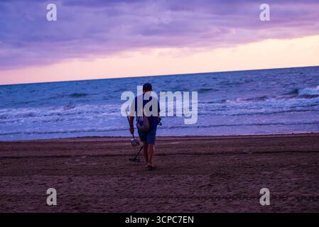 Uomo che pettina la spiaggia con il metal detector Foto Stock