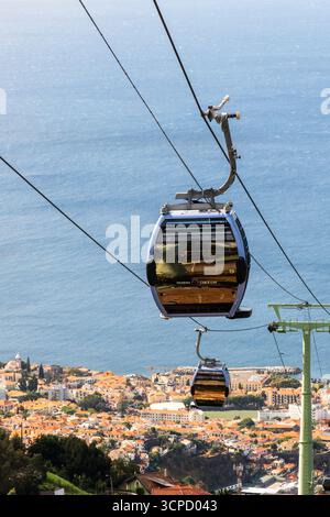 Una funivia di Madeira, identificata come l'auto numero 19, trasporta i passeggeri sulla pittoresca città di Funchal, offrendo vedute panoramiche del tetto rosso Foto Stock