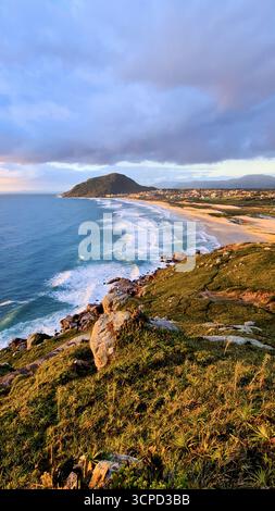 Vista paradisiaca della spiaggia di Santinho a Florianópolis Santa Catarina all'alba, alba sul mare vista dalla cima della montagna. Foto Stock