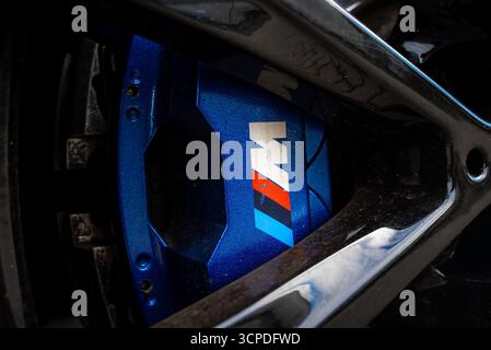 Primo piano della pinza freno BMW M e del cerchione ruota nero lucido Foto Stock