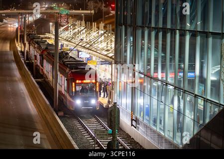 Calgary, Alberta Canada, 20 aprile 2025: Treno di transito rapido che raccoglie passeggeri durante la sera in un terminal di transito. Foto Stock