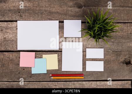 Cancelleria vuota e note colorate disposte su un rustico tavolo in legno in uno spazio di lavoro creativo Foto Stock