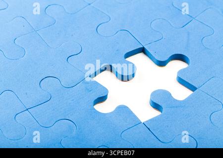 Pezzo del puzzle mancante da un puzzle blu in vista ravvicinata Foto Stock