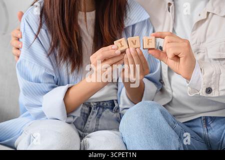 Giovane coppia con abbreviazione IVF seduta sul divano in clinica, primo piano Foto Stock