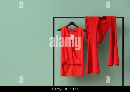 Scaffale con abiti rossi e cartellino di vendita su sfondo verde Foto Stock