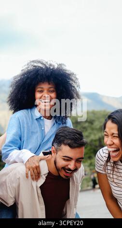 Giovani e diversi amici che si divertono nel parco pubblico. Amicizia e concetto multirazziale. Foto verticale Foto Stock