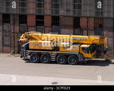 Grande gru mobile gialla della società Scheers parcheggiata di fronte allo storico edificio industriale presso il sito di estrazione del carbone beMine. Foto Stock