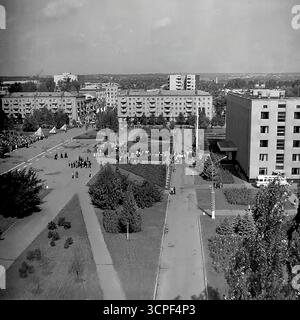 Una vista ad alto angolo cattura una dimostrazione pubblica su larga scala per una festa sovietica in Piazza della Rivoluzione d'ottobre (ora Piazza Soborna) a Sloviansk, RSS Ucraina, negli anni '1970 Questa foto d'archivio monocromatica mostra colonne di dimostranti riunite intorno al monumento centrale di Lenin, una tipica scena di una parata organizzata dallo stato come il giorno di maggio. La vista panoramica della piazza principale della città, circondata da edifici amministrativi e residenziali, incarna la vita ideologica e civica dell'URSS Foto Stock