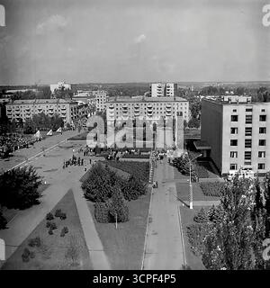 Una vista ad alto angolo cattura una dimostrazione pubblica su larga scala per una festa sovietica in Piazza della Rivoluzione d'ottobre (ora Piazza Soborna) a Sloviansk, RSS Ucraina, negli anni '1970 Questa foto d'archivio monocromatica mostra colonne di dimostranti riunite intorno al monumento centrale di Lenin, una tipica scena di una parata organizzata dallo stato come il giorno di maggio. La vista panoramica della piazza principale della città, circondata da edifici amministrativi e residenziali, incarna la vita ideologica e civica dell'URSS Foto Stock