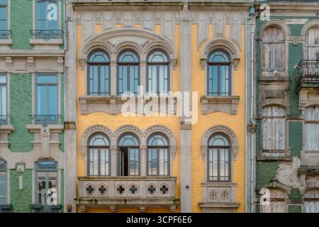 Facciata dell'edificio Porto con mattoni gialli, finestre ad arco simmetriche e balcone in pietra ornato in Portogallo. Downtown Street Scene, Neo-Classical Foto Stock