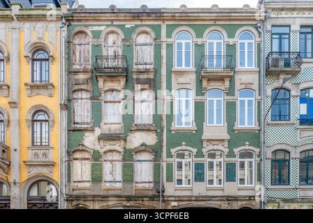 Giustapposizione di facciate restaurate e abbandonate dell'edificio Porto con piastrelle verdi Azulejo in Portogallo. Contrasto architettonico, rinnovamento urbano Foto Stock
