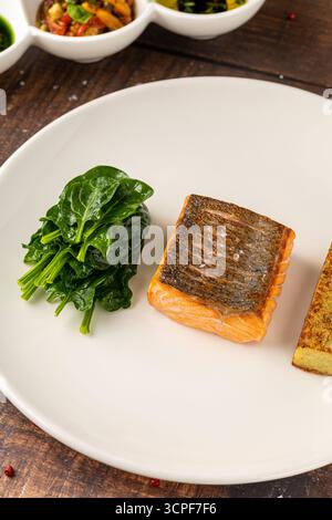 Filetto di salmone scottato servito con spinaci saltati e croquette di patate Foto Stock