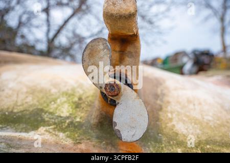 Primo piano di una vecchia elica arrugginita su una superficie resistente agli agenti atmosferici. Lama di elica marina vintage con corrosione su vascello abbandonato Foto Stock