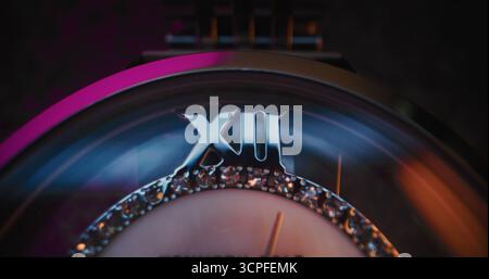 Primo piano di un elegante orologio da polso con lunetta in pietra preziosa e bracciale metallizzato che mostra l'ora esatta. Accessorio che simboleggia il design di lusso, la precisione, la moda e il concetto simbolico del tempo in stile moderno. Foto Stock