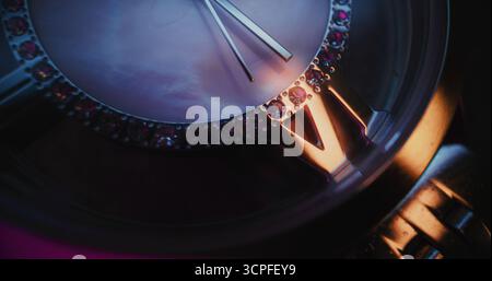 Primo piano di un elegante orologio da polso con lunetta in pietra preziosa e bracciale metallizzato che mostra l'ora esatta. Accessorio che simboleggia il design di lusso, la precisione, la moda e il concetto simbolico del tempo in stile moderno. Foto Stock