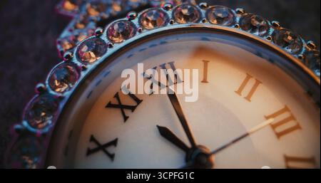 Primo piano dell'orologio decorativo con numeri romani e cornice gioiellata decorata che mostra l'ora. Design elegante ed elegante che simboleggia la tradizione, lo stile di vita di lusso, la misurazione simbolica del tempo. Temporizzato. Foto Stock