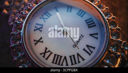 Primo piano dell'orologio decorativo con numeri romani e cornice gioiellata decorata che mostra l'ora esatta. Design elegante che simboleggia eleganza, lusso, puntualità, tradizione. Concetto simbolico di misurazione del tempo Foto Stock