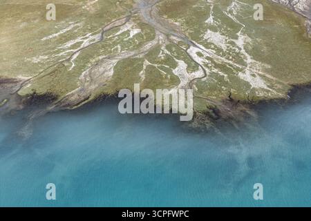 Vista aerea delle acque turchesi che incontrano il terreno aspro e erboso, dove tortuosi ruscelli intagliano intricati motivi nel paesaggio, lago Baisha, Xinjiang, Cina. Foto Stock