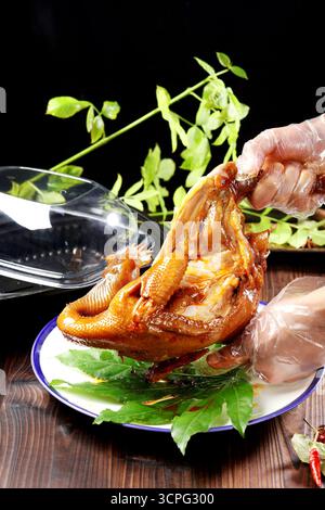 Mani con guanti per servire pollo arrosto in stile cinese con scatola da asporto Foto Stock