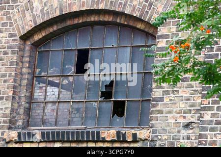 Finestra rotta in un vecchio edificio in mattoni della fabbrica Weathered Foto Stock