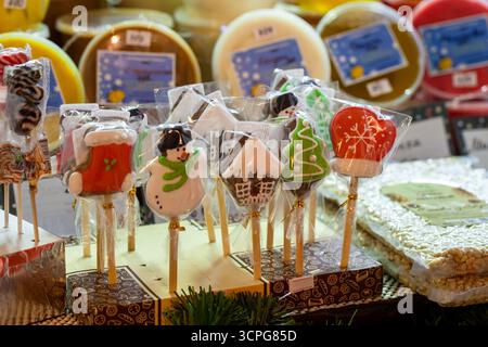 Vivaci prelibatezze natalizie su bastoncini, tra cui pupazzo di neve, albero di natale e biscotti della casa avvolti in borse trasparenti, colori brillanti e decorazioni natalizie a mar Foto Stock