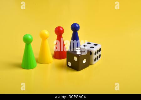 Coloratissime chip di gioco e due dadi isolati su uno sfondo giallo Foto Stock