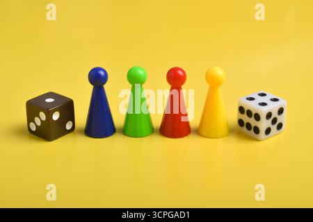 Coloratissime chip di gioco e due dadi isolati su uno sfondo giallo Foto Stock