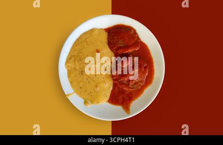 Un piatto di due sostanziose polpette soffocate in una ricca salsa di pomodoro. Servito insieme a una generosa porzione di crema di patate. Foto Stock