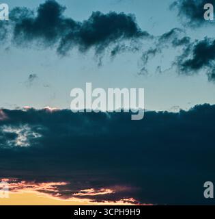 Sereno cielo serale, pieno di soffici nuvole scintillanti in incantevoli colori del crepuscolo, che irradiano calma, magia e bellezza naturale. Foto Stock