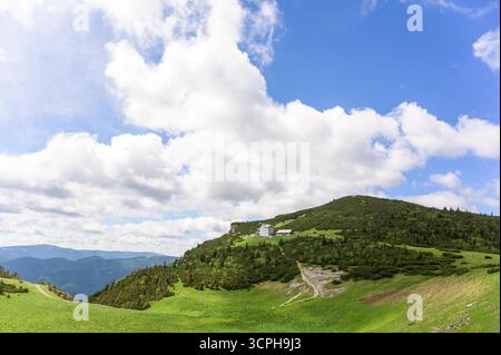 Paesaggio vivace che mostra la montagna di Rax in Austria con colline verdi ondulate e macchie di foresta Foto Stock