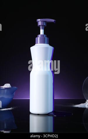 Prodotto cosmetico per la cura dei capelli per capelli biondi e polvere su superficie a specchio nera su sfondo viola scuro Foto Stock