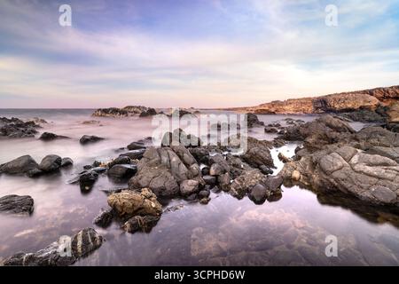 Costa rocciosa lungo il litorale di Aruba con oceano, rocce e tramonto Foto Stock