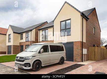 Moderne case residenziali con un furgone T6 volkswagen parcheggiato in un quartiere periferico in una giornata nuvolosa - proprietà abitativa Foto Stock