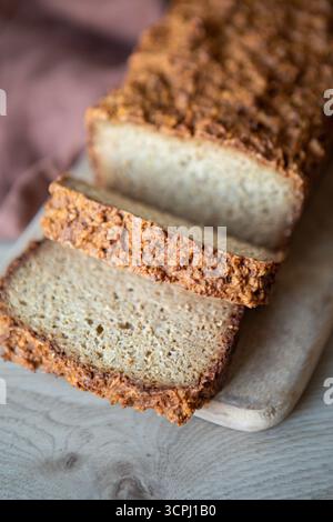 pane di grano intero appena sfornato su un piccolo tagliere di legno. La pagnotta ha una crosta rustica e rustica molto rustica e morbida all'interno Foto Stock