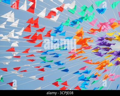 Bandiere colorate e aeroplani creano un'atmosfera vivace contro un cielo azzurro. La scena cattura un'atmosfera festosa, ideale per feste ed ev Foto Stock