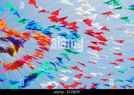 Bandiere colorate e aeroplani creano un'atmosfera vivace contro un cielo azzurro. La scena cattura un'atmosfera festosa, ideale per feste ed ev Foto Stock