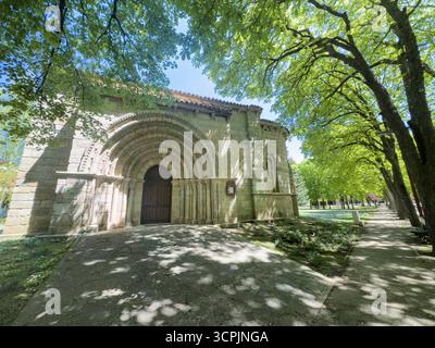 Ingresso romanico di uno storico eremo a Palencia circondato da alberi e luce soffusa Foto Stock