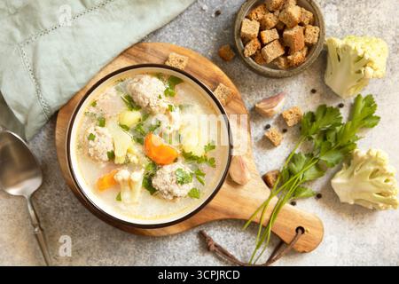 Abbondante zuppa di polpette con verdure ed erbe aromatiche per un pasto accogliente. Sfondo piatto della vista superiore. Foto Stock