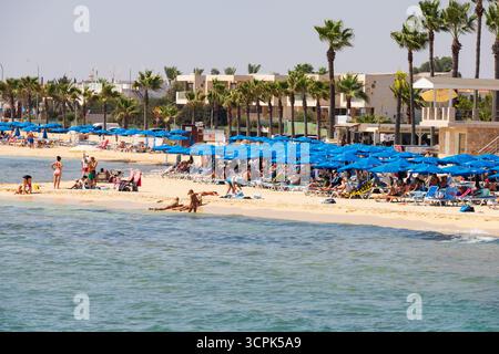 Turisti che prendono il sole e nuotano alla spiaggia di Agia Thekla, vicino a Sotira e Agia Napa, Cipro. Foto Stock