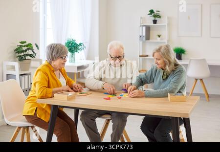 Gruppo di tre donne anziane e un uomo che raccolgono mosaici, mettendo insieme forme geometriche Foto Stock