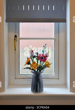 I colorati fiori Lego adornano il davanzale della finestra. Foto Stock