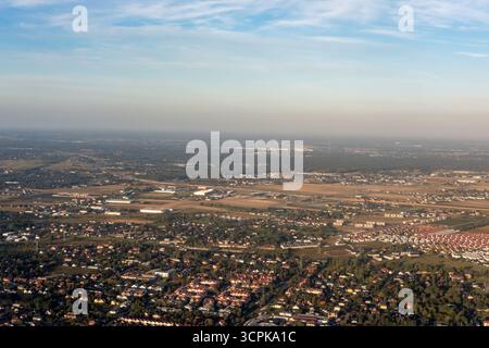 Vista aerea dei tetti e degli alberi verdeggianti che si estendono attraverso il paesaggio sotto un cielo morbido e nebuloso, Varsavia, Voivodato della Masovia, Polonia. Foto Stock