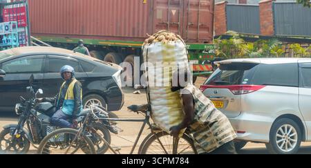 Kigali Rwanda - 3 settembre 2025; scena urbana e di strada nella città africana dove l'uomo spinge un sacco grande sulla patata sul retro della bicicletta . Foto Stock