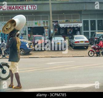 Kigali Rwanda - 3 settembre 2025; scena urbana e di strada nella città africana con un uomo che porta un vecchio gabinetto in mezzo alla strada. Foto Stock