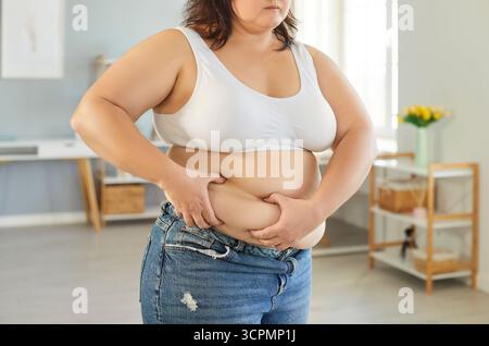 Donna in sovrappeso irriconoscibile che afferra la pelle sulla pancia grassa Foto Stock