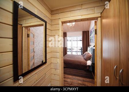 Accogliente camera da letto in legno con specchio e guardaroba Foto Stock