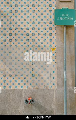 Piastrelle tradizionali portoghesi di Azulejo con motivo floreale blu e giallo e cartello stradale a Porto. Motivo in ceramica, simbolo del Portogallo, texture urbana Foto Stock